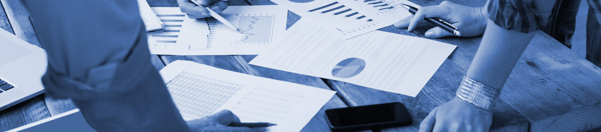People looking at printed spreadsheets on a table